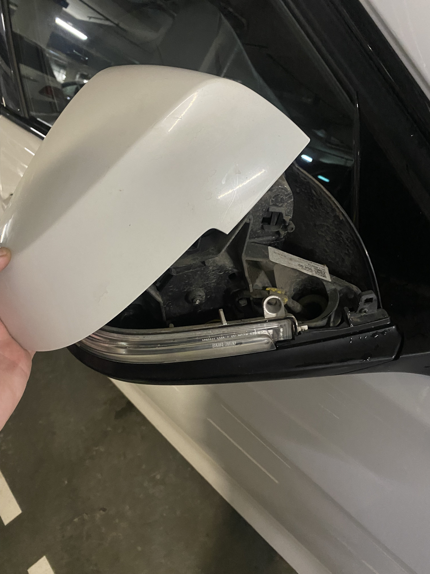 Daļēji noņemts BMW sānu spoguļa vāciņš atsedz korpusu